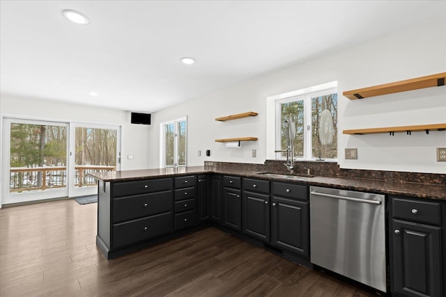 kitchen featuring sink, dishwasher, dark stone countertops, dark hardwood / wood-style flooring, and kitchen peninsula