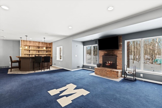 unfurnished living room featuring dark carpet, a fireplace, and bar area