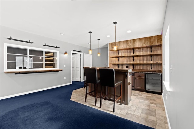 bar with decorative light fixtures, wooden walls, beverage cooler, and a barn door