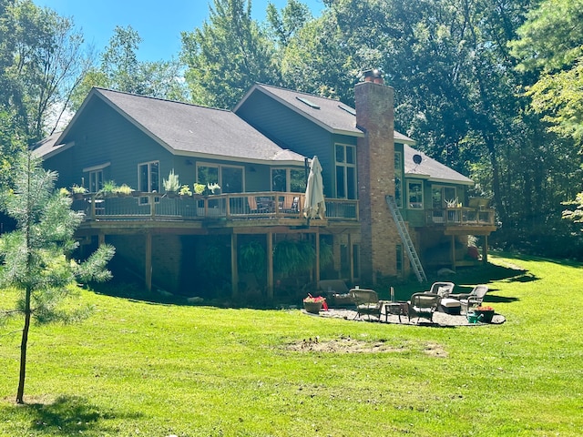 rear view of property featuring a deck, a patio, and a lawn