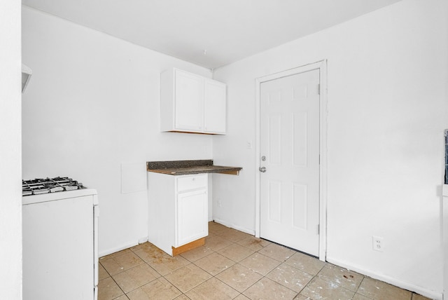 kitchen featuring light tile patterned flooring, white gas range, and white cabinets