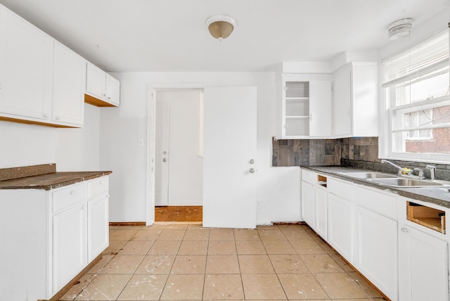 kitchen with backsplash, light tile patterned flooring, sink, and white cabinets