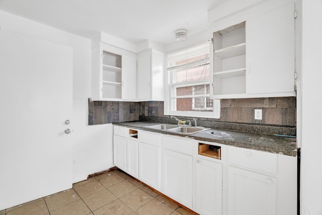 kitchen with tasteful backsplash, sink, light tile patterned floors, and white cabinets