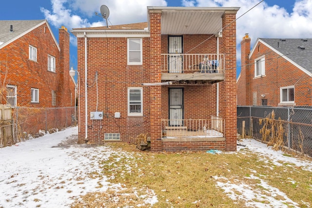 snow covered back of property featuring a balcony