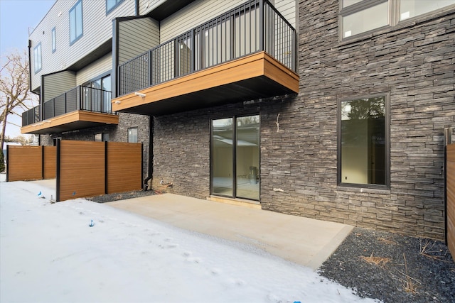 snow covered house featuring a patio area