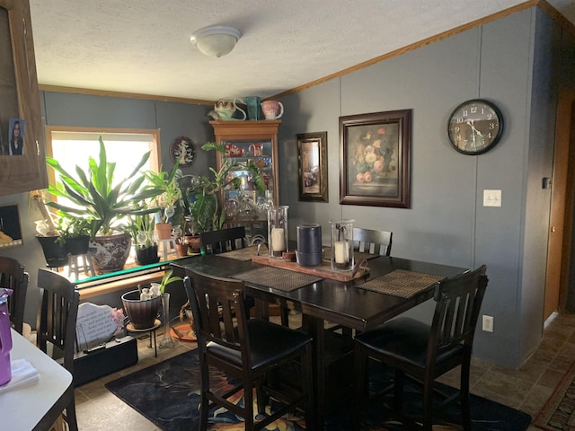 dining area with lofted ceiling, ornamental molding, and a textured ceiling