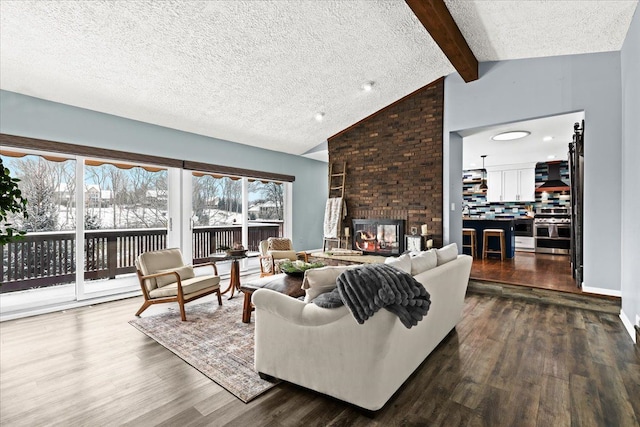 living room with a brick fireplace, a textured ceiling, wood-type flooring, and vaulted ceiling with beams