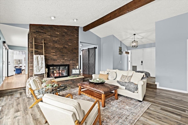 living room featuring a brick fireplace, a notable chandelier, wood-type flooring, a textured ceiling, and lofted ceiling with beams