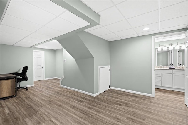 home office featuring light wood-type flooring, a drop ceiling, and sink