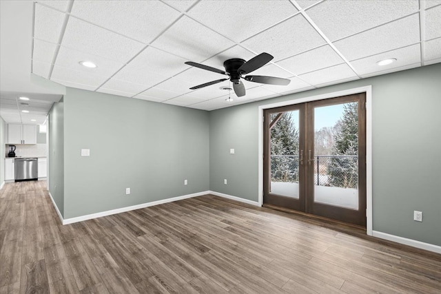 empty room with ceiling fan, a paneled ceiling, french doors, and wood-type flooring