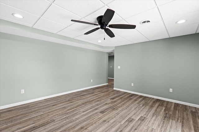 empty room featuring a paneled ceiling, wood-type flooring, and ceiling fan