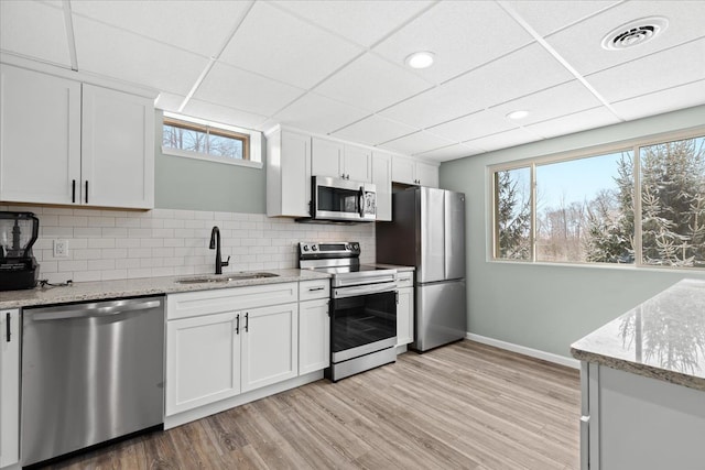 kitchen featuring a drop ceiling, sink, stainless steel appliances, and white cabinetry