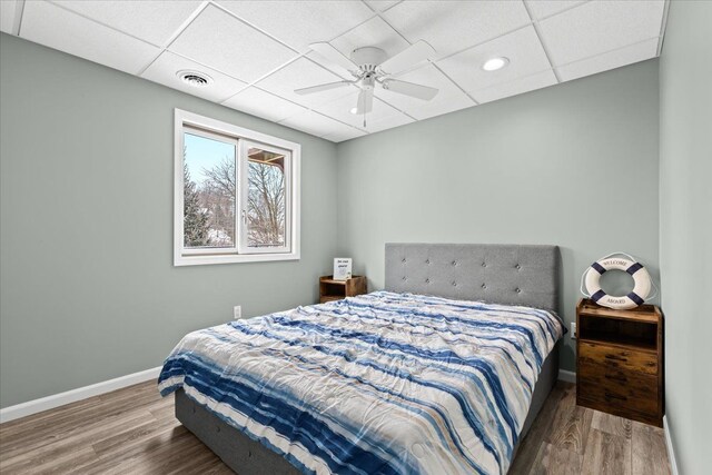 bedroom featuring ceiling fan, hardwood / wood-style floors, and a paneled ceiling