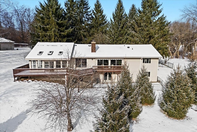 snow covered rear of property featuring a deck