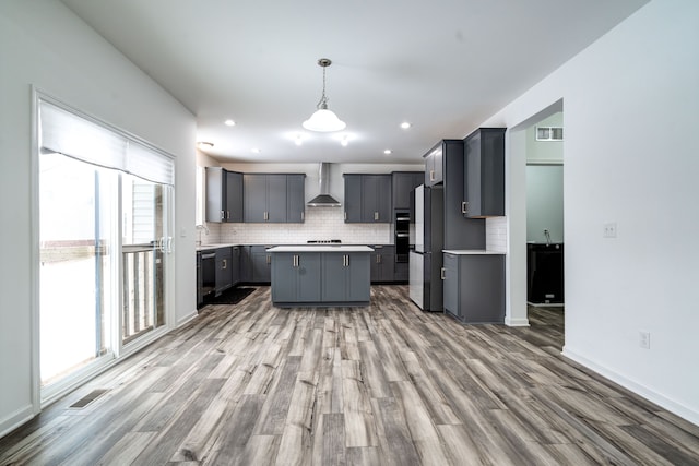 kitchen featuring wall chimney range hood, gray cabinets, a center island, black dishwasher, and hanging light fixtures