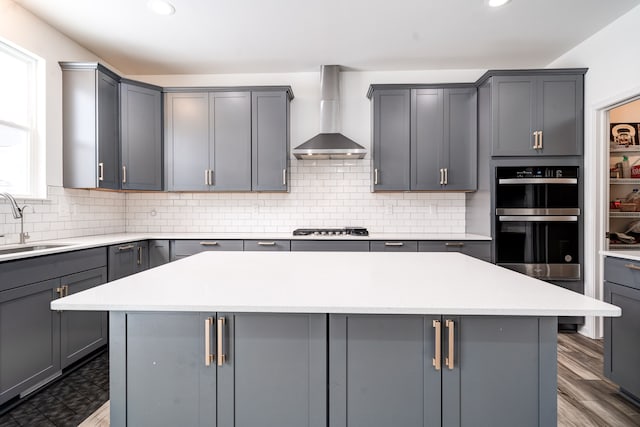 kitchen featuring a kitchen island, gray cabinetry, and wall chimney range hood