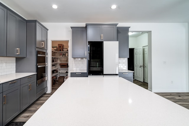 kitchen featuring black refrigerator, tasteful backsplash, and gray cabinets