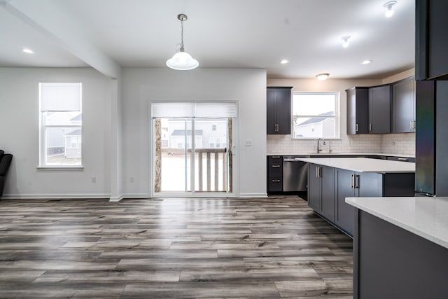 kitchen featuring dishwasher, pendant lighting, decorative backsplash, sink, and dark hardwood / wood-style flooring