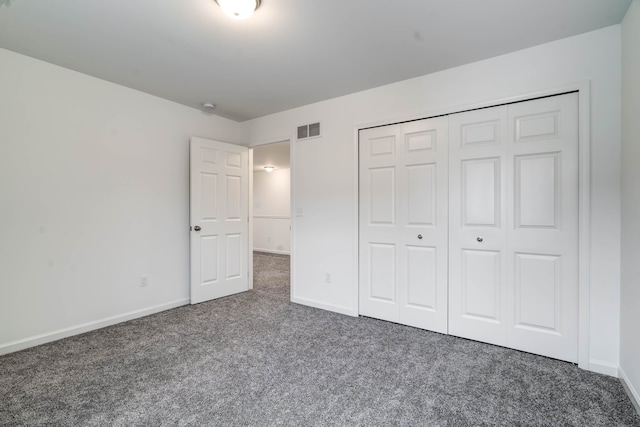 unfurnished bedroom featuring a closet and dark carpet