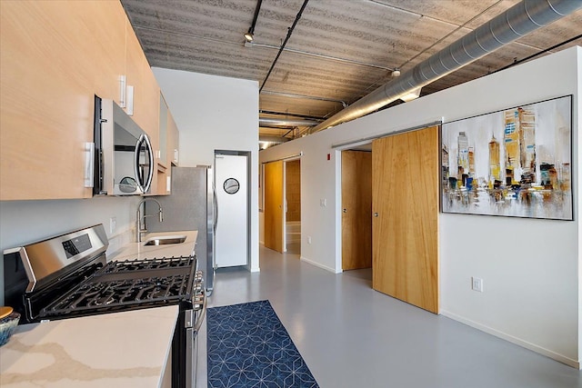 kitchen featuring concrete flooring, appliances with stainless steel finishes, track lighting, and sink