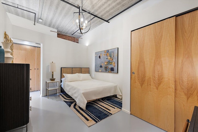 bedroom featuring an inviting chandelier and concrete flooring