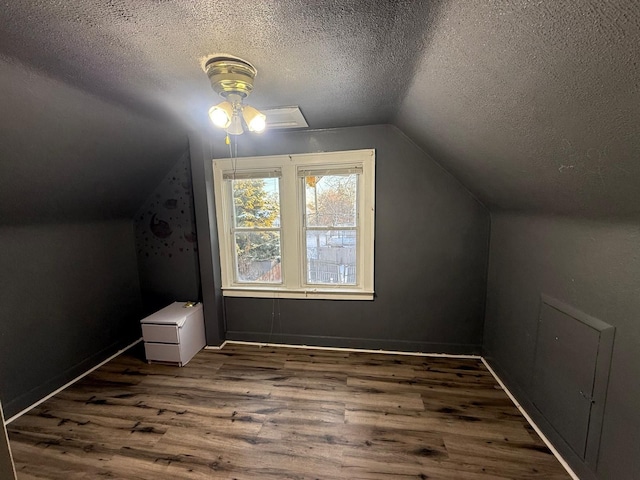 bonus room with vaulted ceiling, dark wood-type flooring, and a textured ceiling