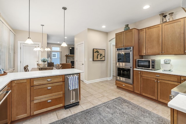 kitchen featuring light tile patterned floors, appliances with stainless steel finishes, a notable chandelier, decorative light fixtures, and a fireplace