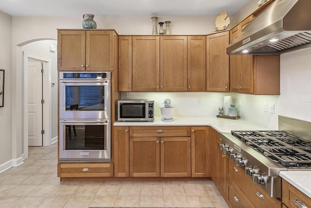 kitchen with backsplash, appliances with stainless steel finishes, and range hood