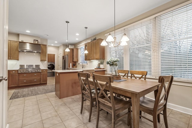 dining space with light tile patterned floors, a chandelier, washer / clothes dryer, and sink