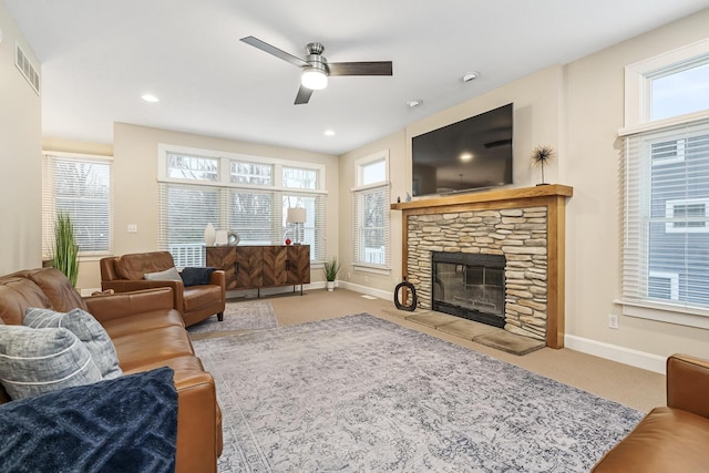 living room with ceiling fan, light colored carpet, and a stone fireplace