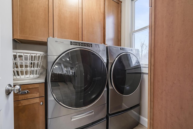 clothes washing area featuring washing machine and dryer and cabinets