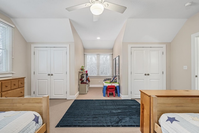 carpeted bedroom featuring ceiling fan, two closets, and multiple windows