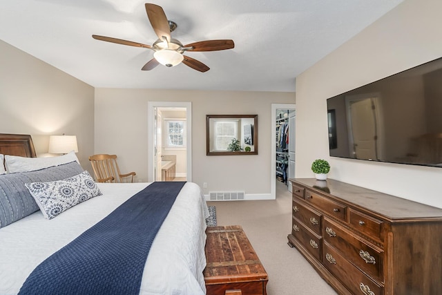 carpeted bedroom featuring ceiling fan, a walk in closet, a closet, and ensuite bath