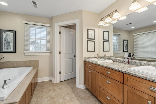 bathroom with tiled bath, tile patterned flooring, and vanity