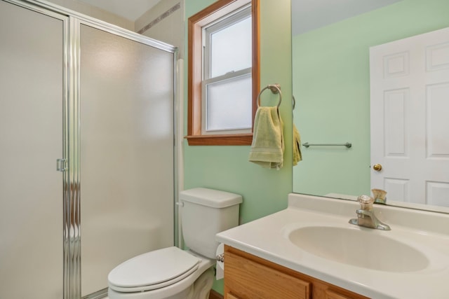 bathroom featuring toilet, vanity, and a shower with shower door