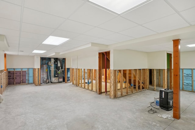 basement featuring water heater, heating unit, and a paneled ceiling