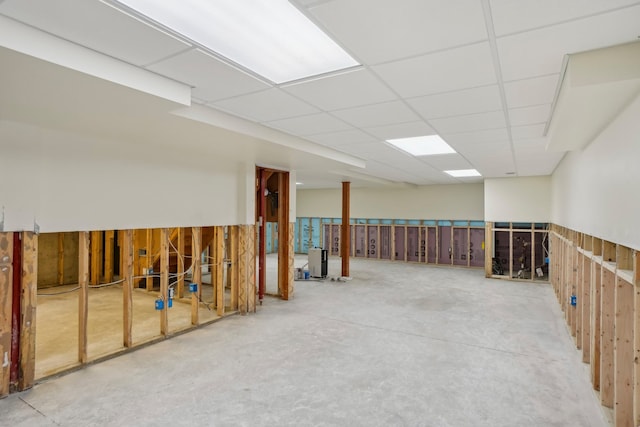 basement featuring a paneled ceiling and wood walls