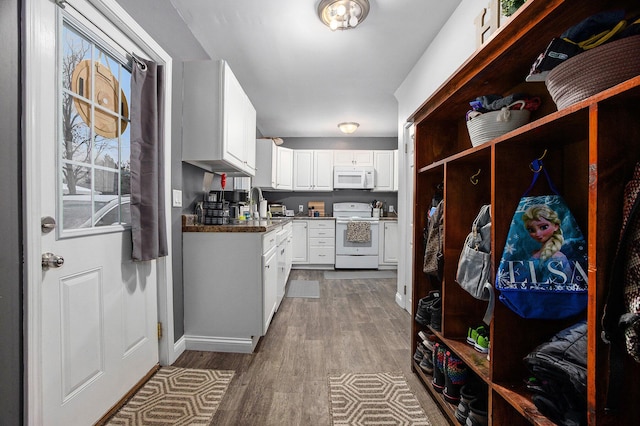 kitchen featuring white cabinetry, sink, white appliances, and hardwood / wood-style flooring