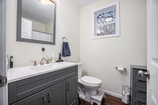 bathroom with wood-type flooring, toilet, and vanity