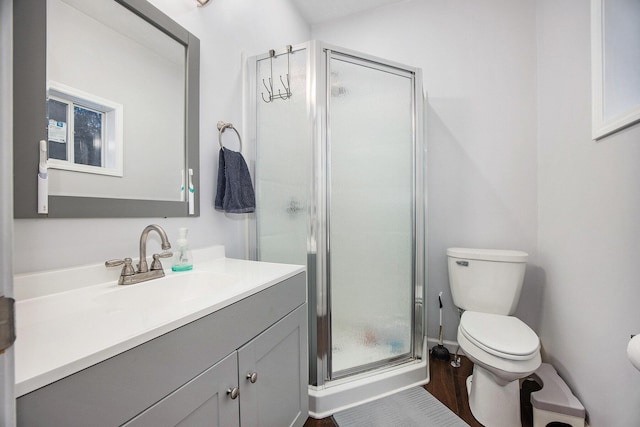 bathroom featuring toilet, a shower with shower door, and vanity