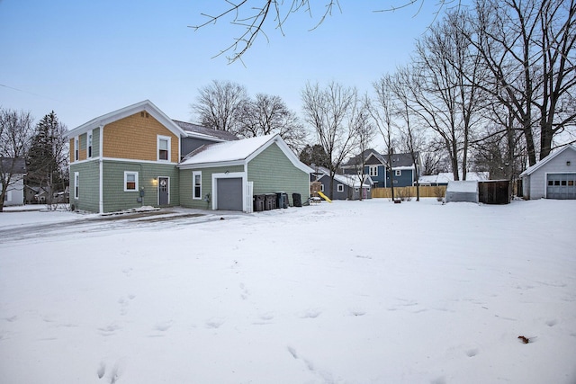 snow covered rear of property with a garage