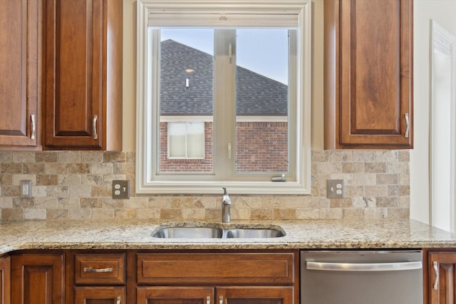 kitchen featuring light stone counters, sink, backsplash, and stainless steel dishwasher