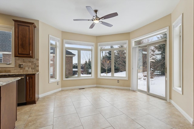 unfurnished dining area featuring ceiling fan, light tile patterned floors, and a healthy amount of sunlight