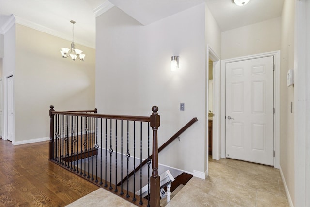 stairway with an inviting chandelier, ornamental molding, and hardwood / wood-style floors