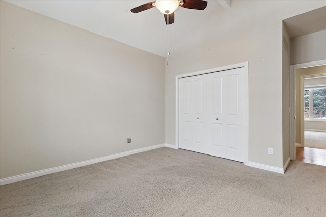 unfurnished bedroom featuring ceiling fan, vaulted ceiling with beams, a closet, and light colored carpet