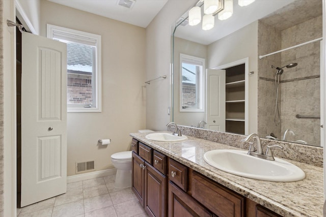 bathroom with toilet, a healthy amount of sunlight, tile patterned floors, and vanity