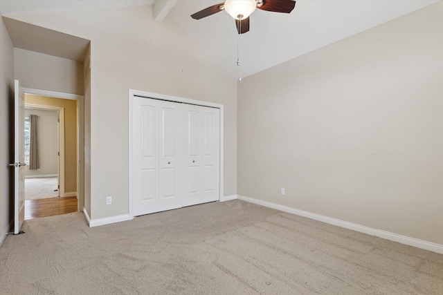 unfurnished bedroom with light carpet, a closet, vaulted ceiling with beams, and ceiling fan