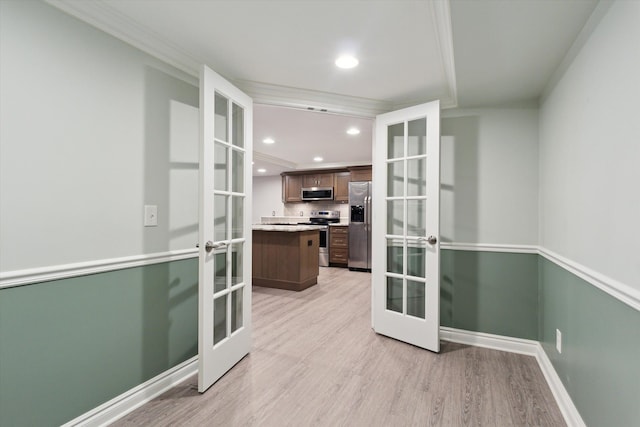 interior space with light wood-type flooring, ornamental molding, and french doors