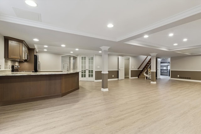 interior space featuring a raised ceiling, light stone countertops, crown molding, and light hardwood / wood-style floors