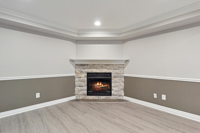 unfurnished living room featuring hardwood / wood-style flooring, a raised ceiling, crown molding, and a fireplace